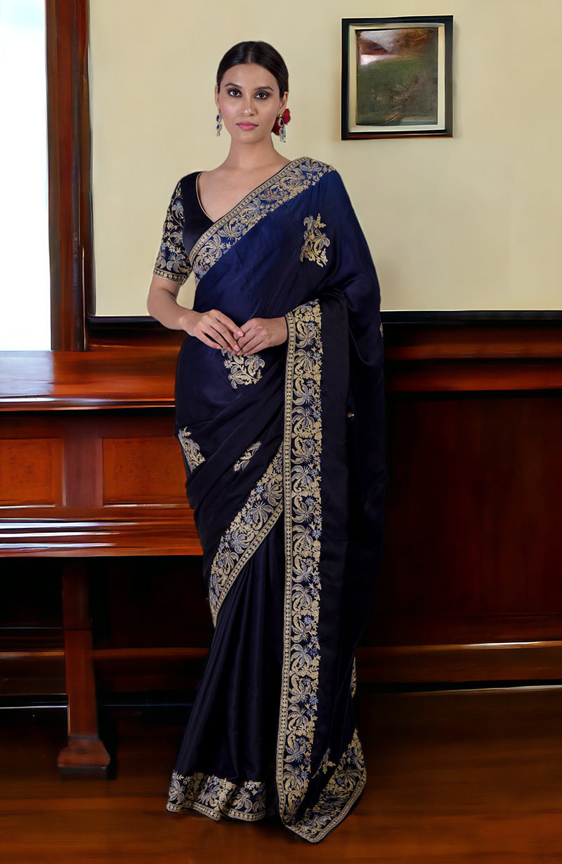 A woman models a midnight blue ombre saree with gold and blue embroidery.