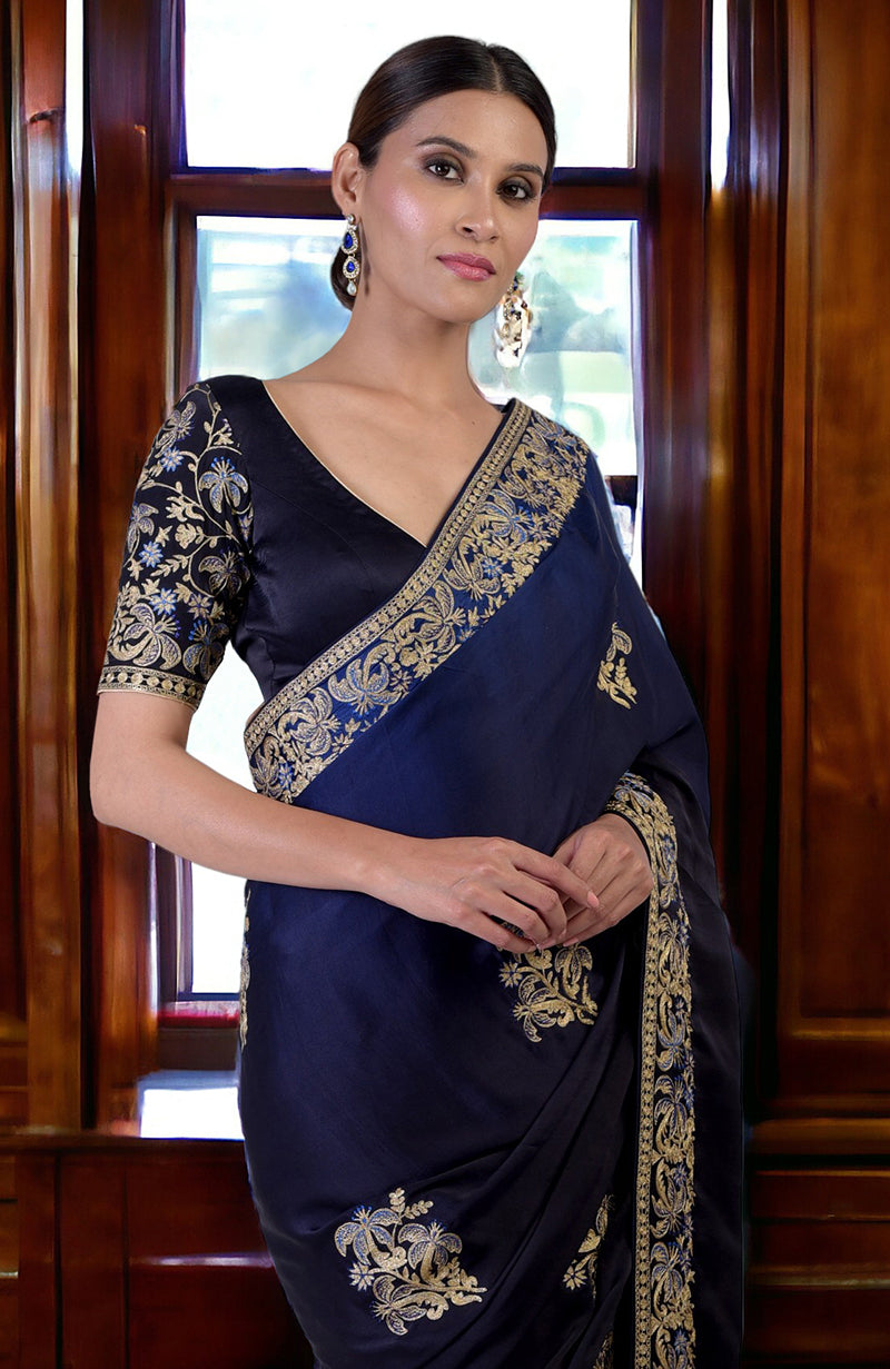 A woman models a midnight blue ombre saree with gold and blue embroidery.