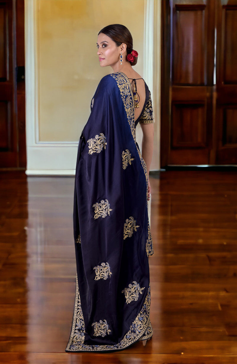 A woman in a midnight blue ombre Kashidakari embroidered saree set looks over her shoulder.