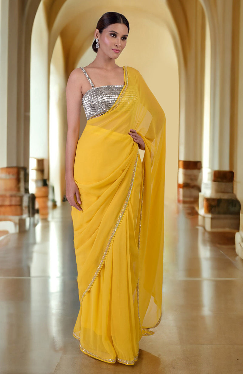 A woman models a daffodil yellow saree with a silver crystal bustier.