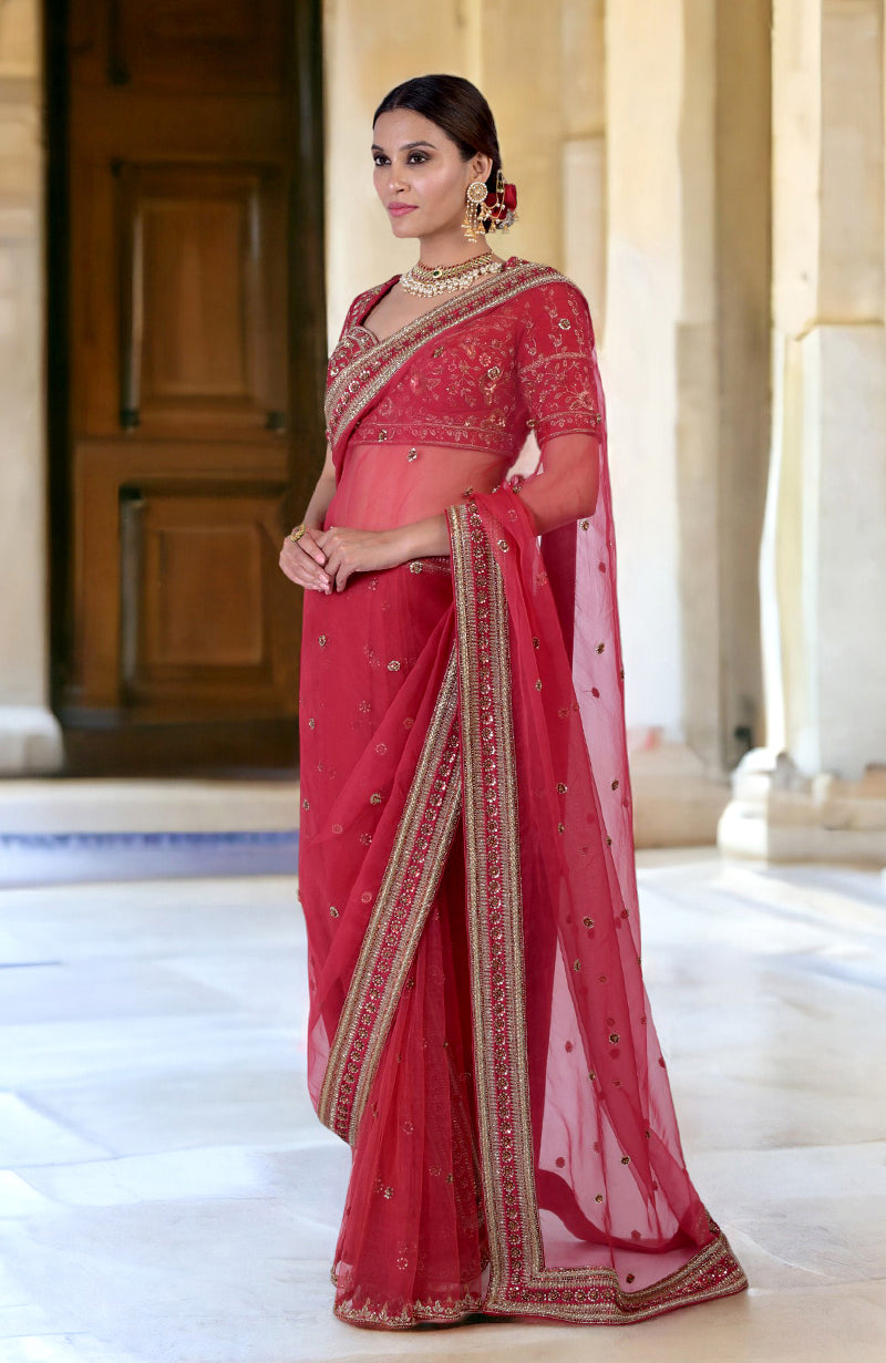 A woman models a ruby red zardozi hand-embroidered saree with a matching blouse.