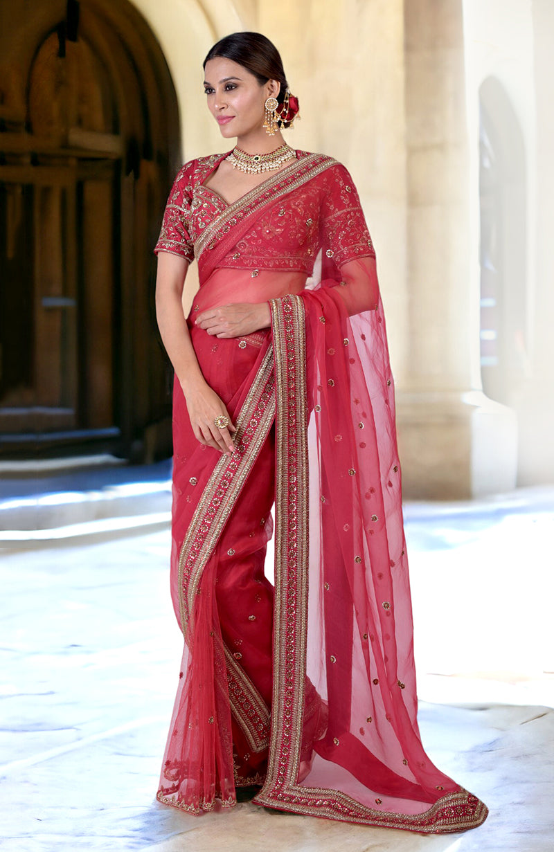 A woman models a ruby red zardozi hand-embroidered saree with a matching blouse.