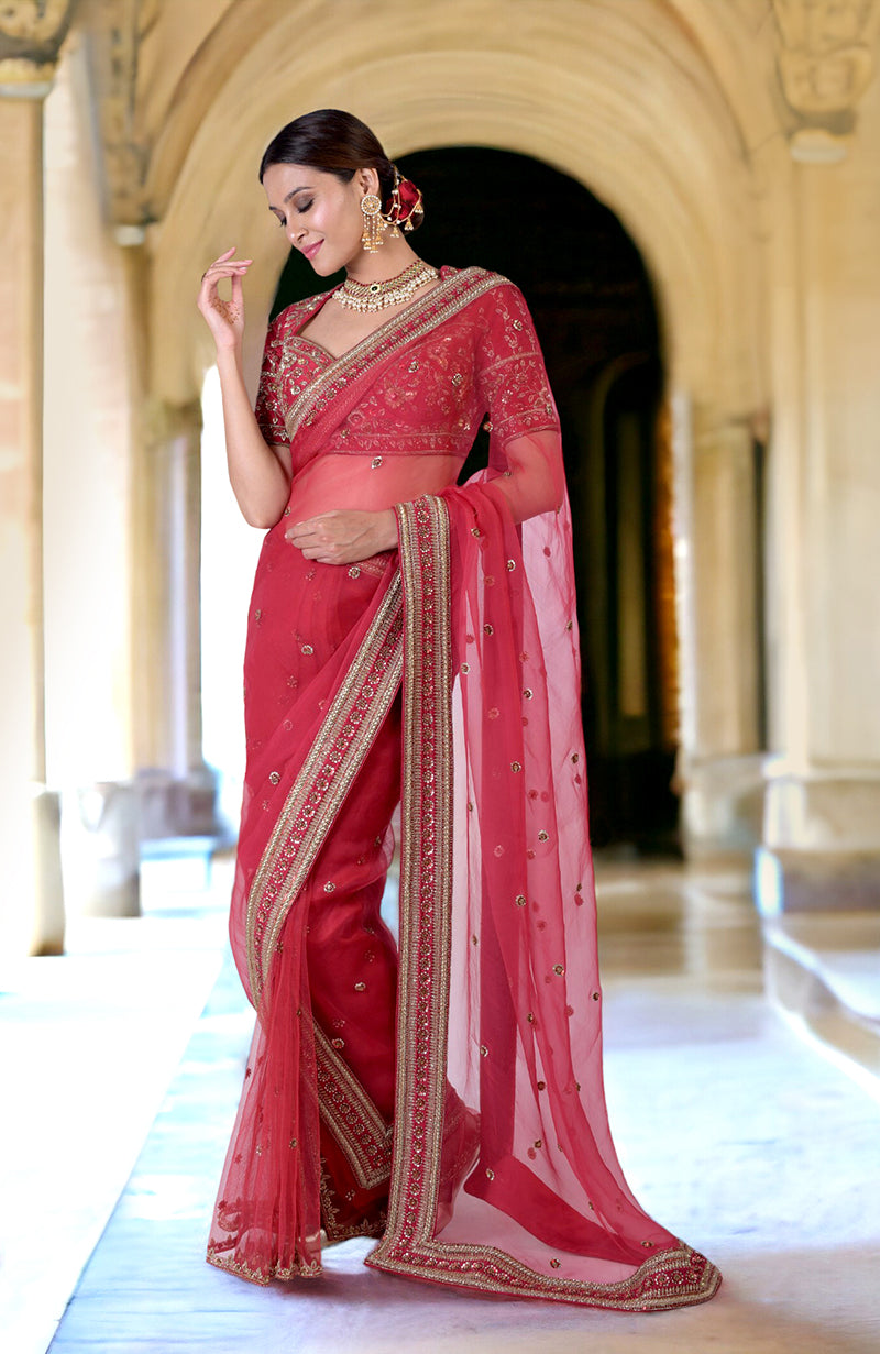 A woman models a ruby red zardozi hand-embroidered saree with a matching blouse.