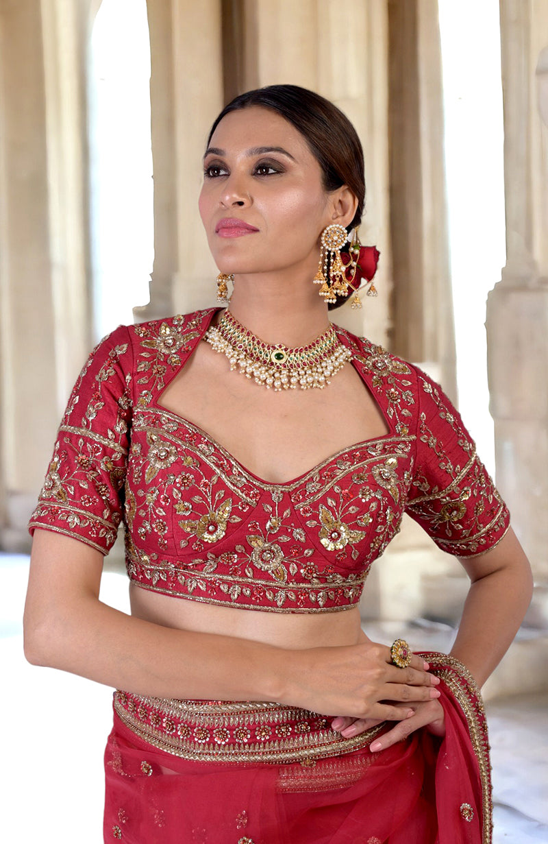 A woman in a ruby red zardozi hand-embroidered saree and matching blouse.