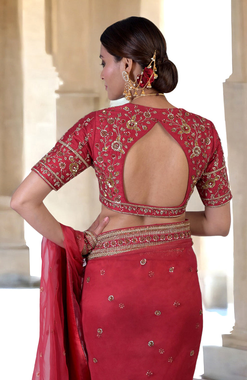 A woman models a ruby red zardozi hand-embroidered saree with an open back.