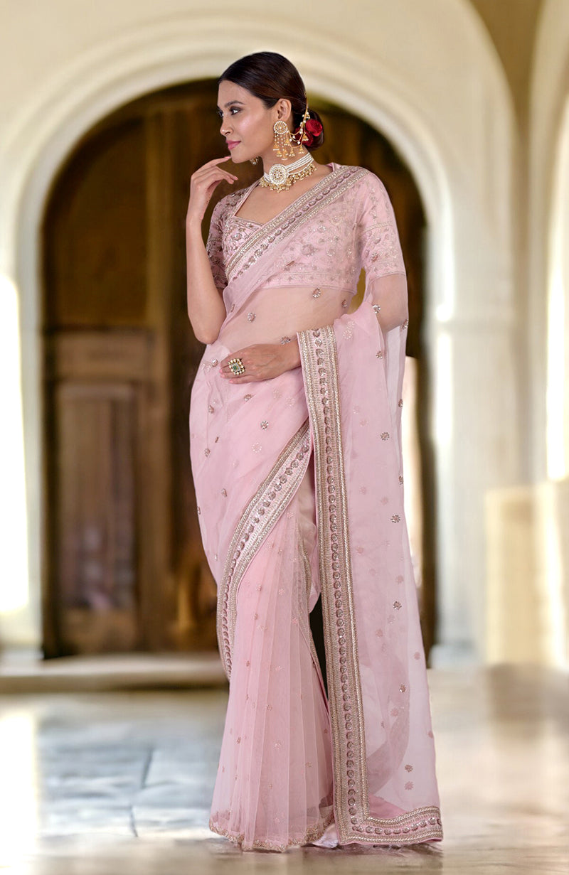 A woman models a rose pink zardozi hand-embroidered saree with a matching blouse.