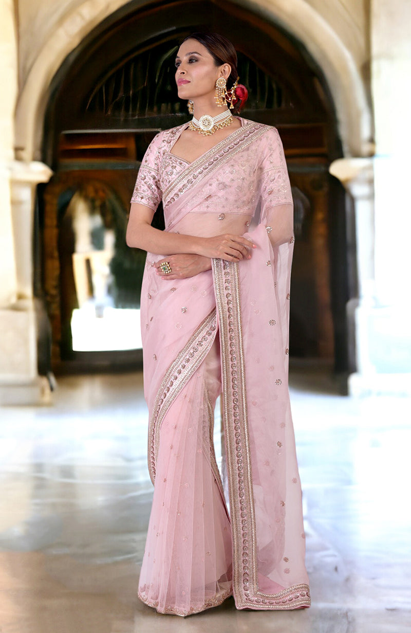 A woman models a rose pink zardozi hand-embroidered saree with a matching blouse.