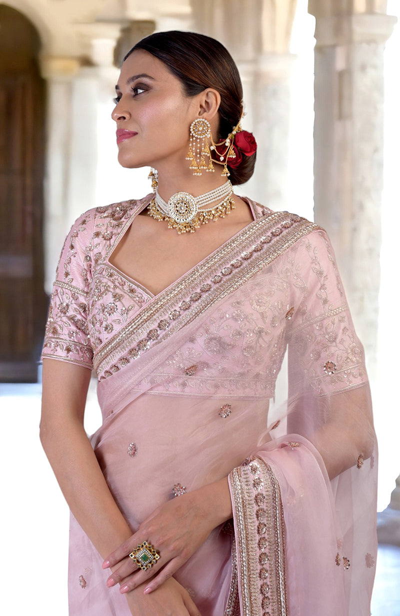 A woman in a rose pink zardozi hand-embroidered saree with a statement necklace.