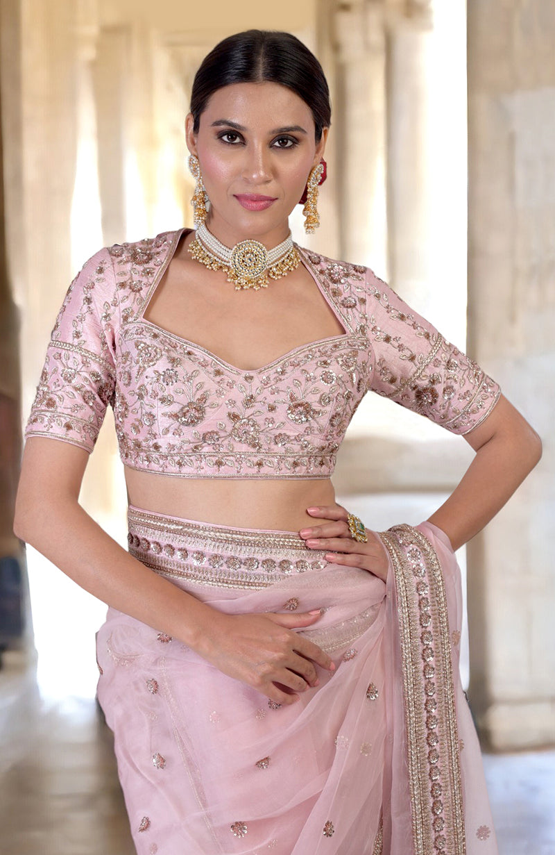 A woman models a rose pink zardozi hand-embroidered saree with a matching blouse.