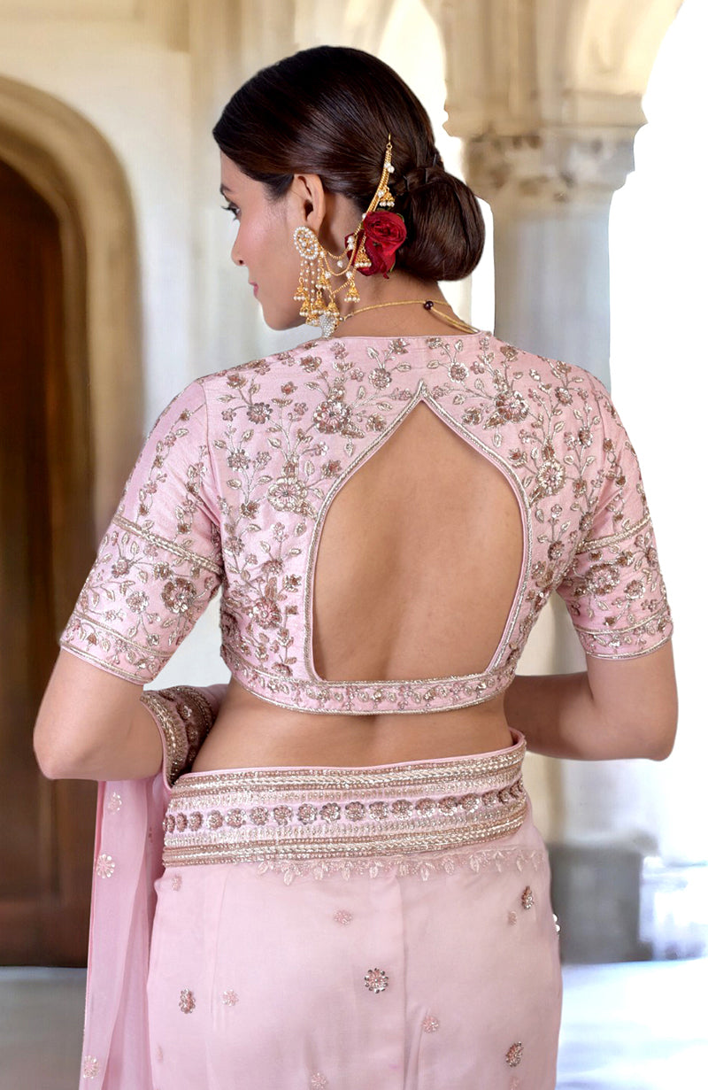 A woman from behind wearing a rose pink zardozi hand-embroidered saree and blouse.