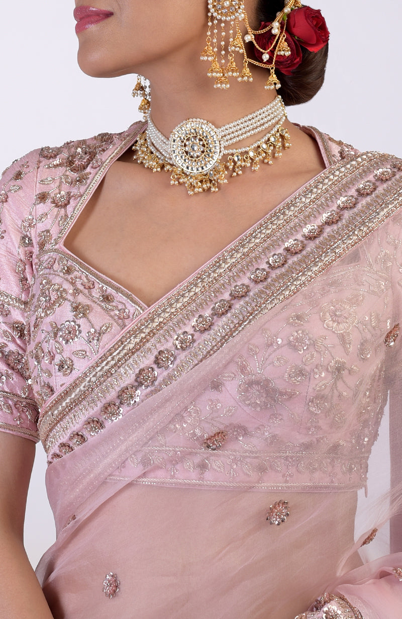 A woman models a rose pink zardozi hand-embroidered saree with a matching blouse.