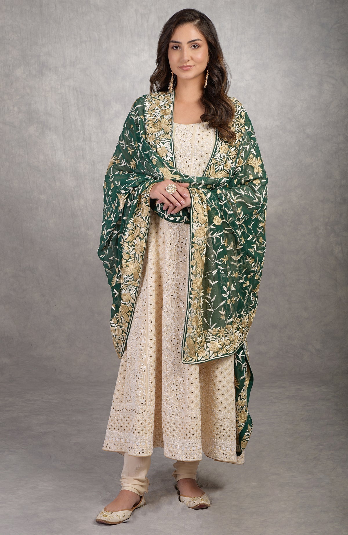 A woman in a champagne chikankari suit with a green Parsi Gara dupatta.