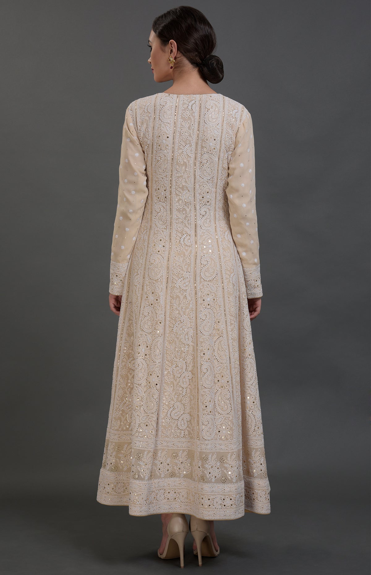 A woman from behind in a champagne chikankari anarkali suit with gold embellishments.