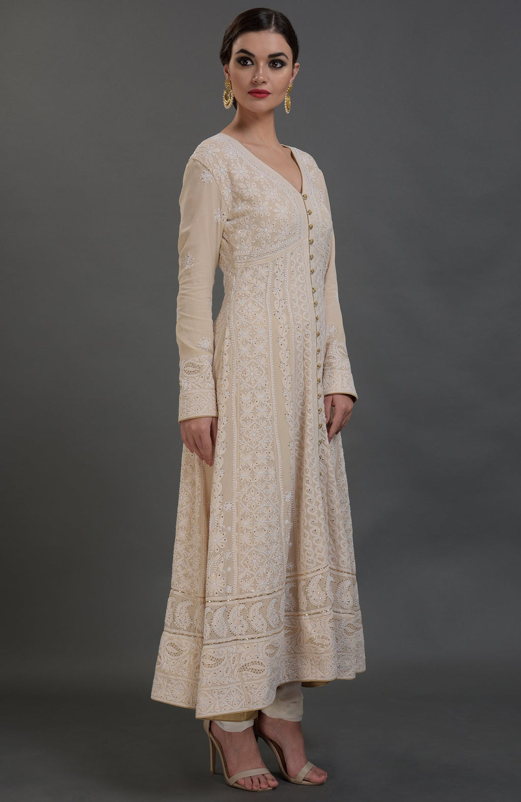A woman models a champagne chikankari suit with a V-neck and long sleeves.