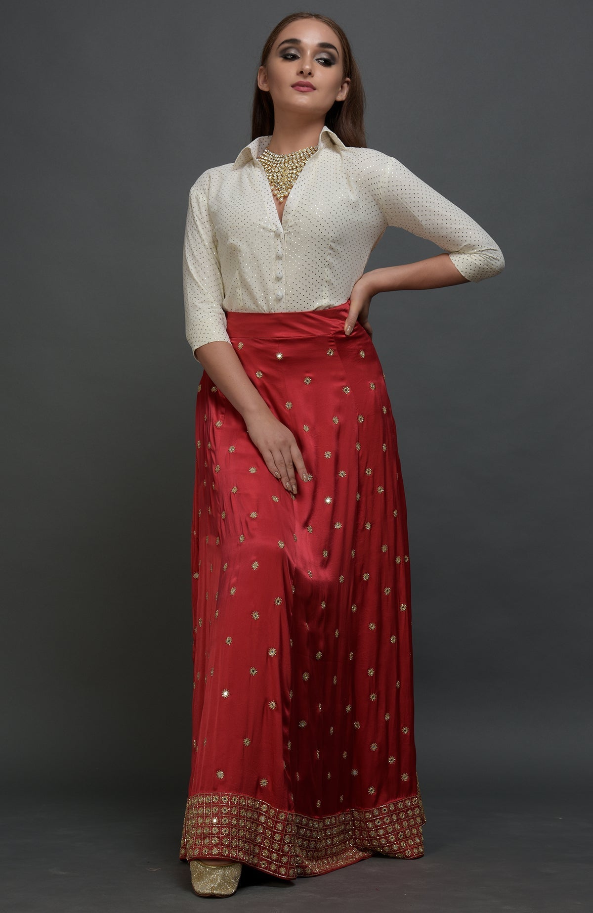 A model wears a red mirror work and zardozi skirt with a mukaish blouse.