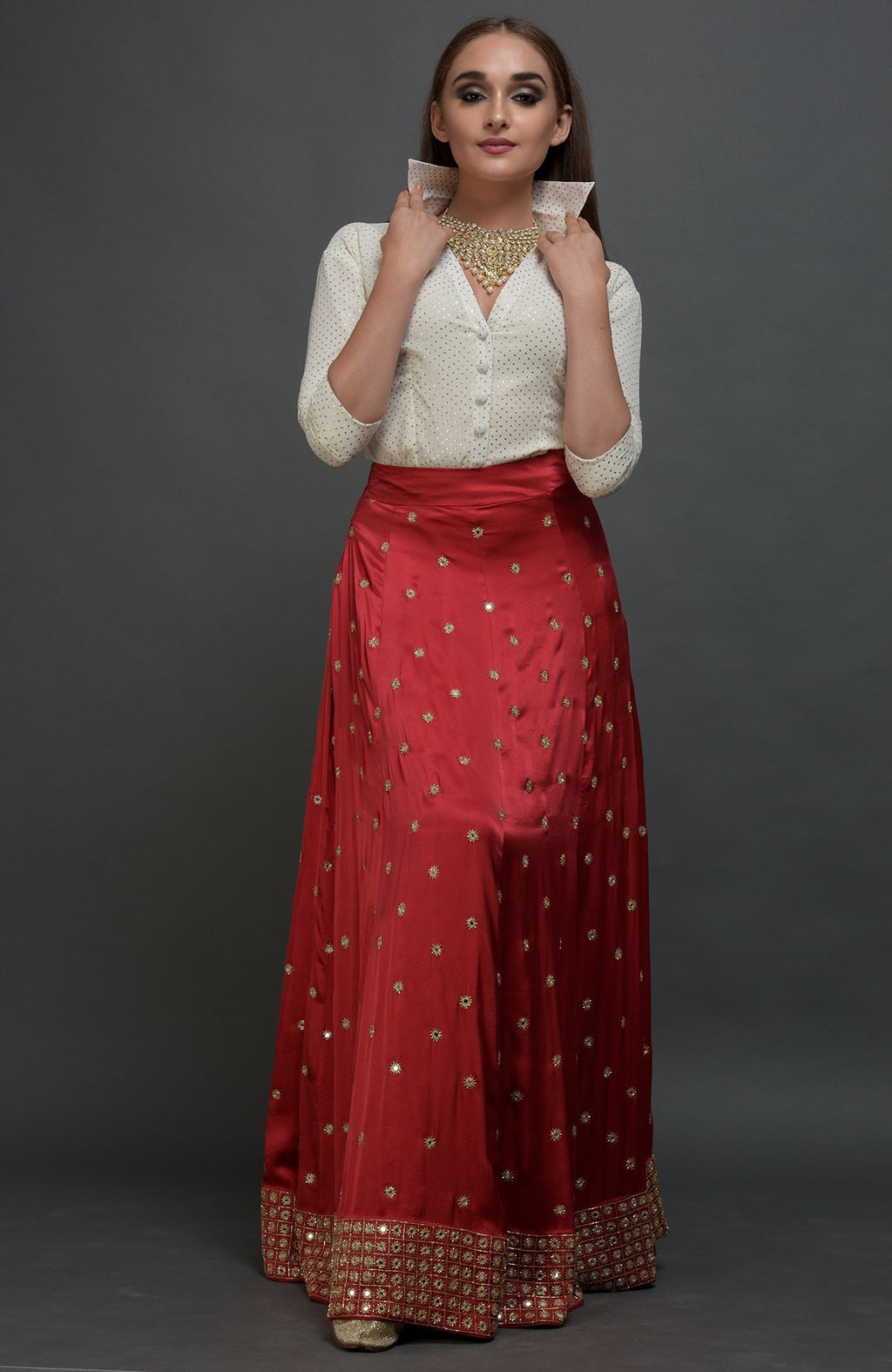 A woman models a red mirror work and zardozi skirt with a mukaish blouse.