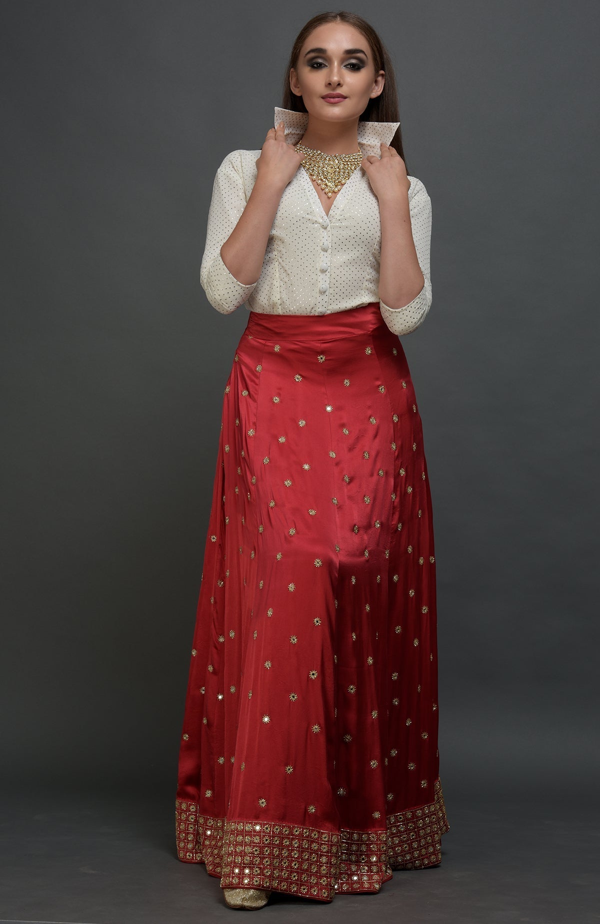 A woman models a red mirror work and zardozi skirt with a mukaish blouse.