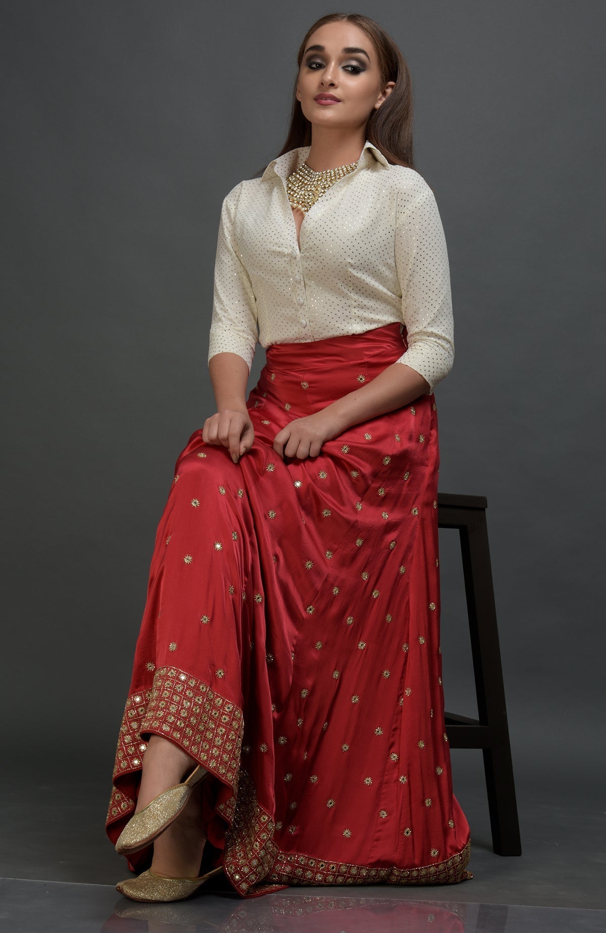 A woman models a red mirror work and zardozi skirt with a mukaish blouse.