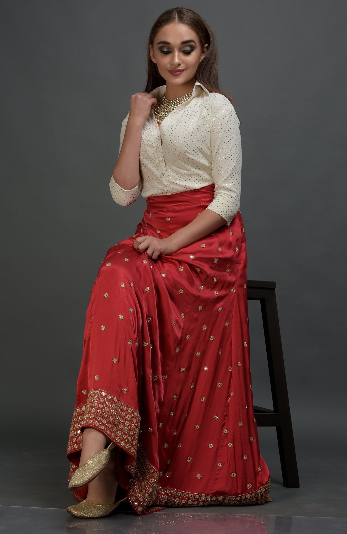 A woman models a red mirror work and zardozi skirt with a mukaish blouse.