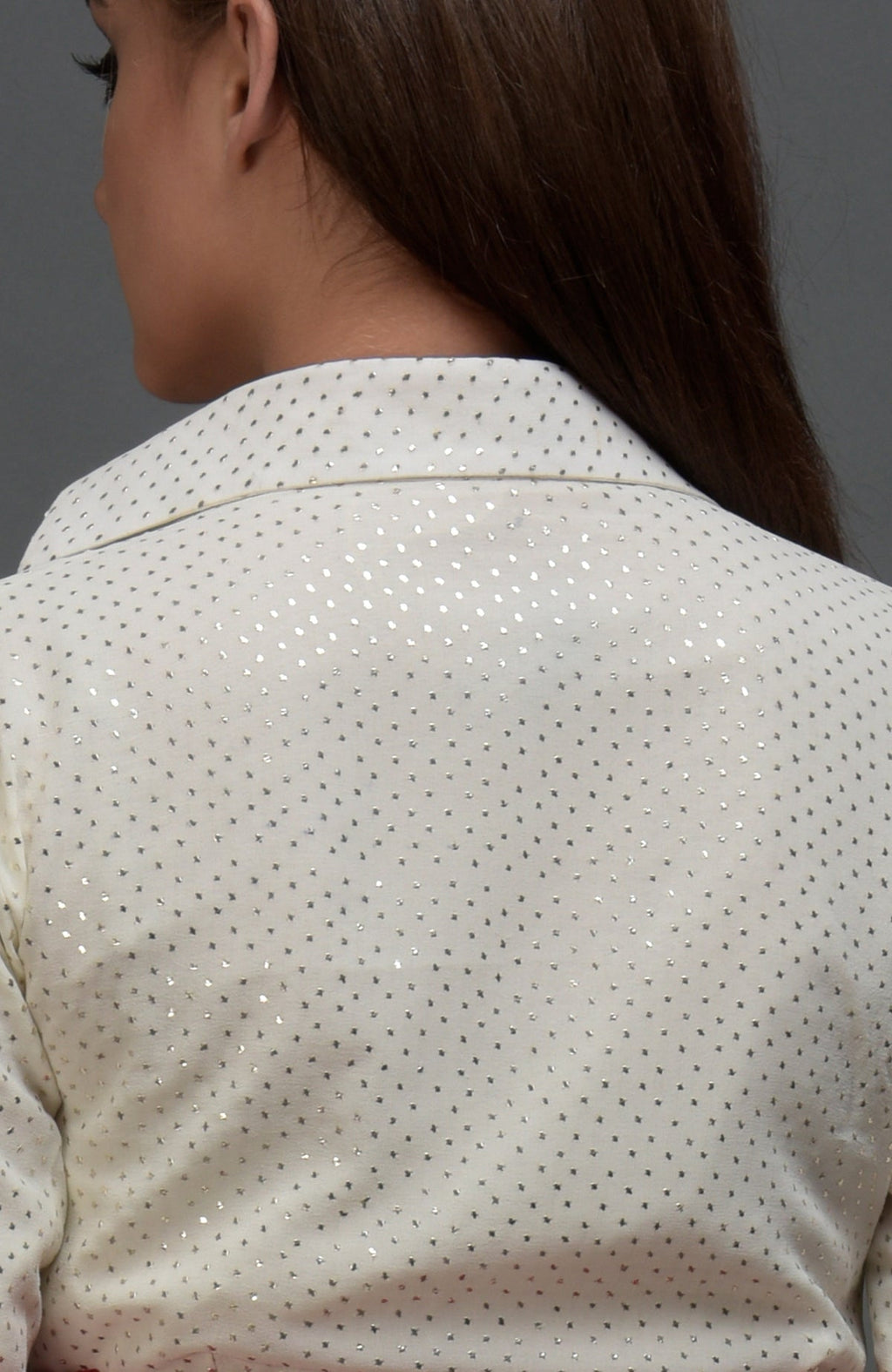 A woman from the back wearing a white blouse with silver polka dots.