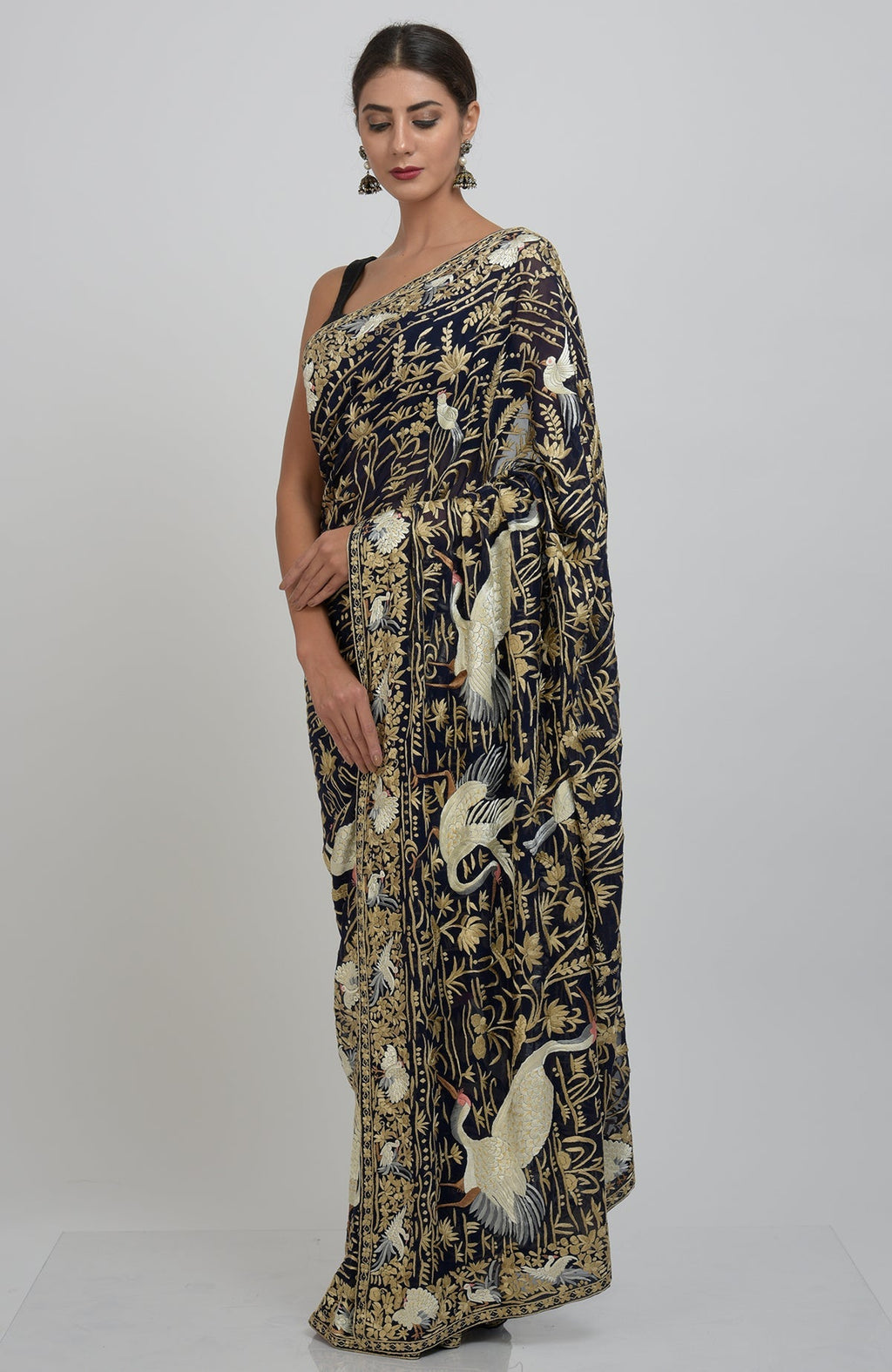 A woman models a midnight blue Parsi Gara hand-embroidered saree with crane and floral motifs.