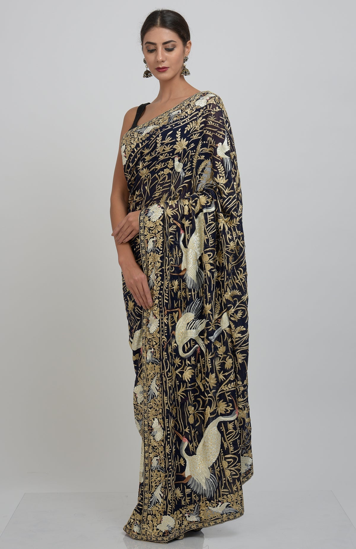 A woman models a midnight blue Parsi Gara hand-embroidered saree with crane and floral motifs.