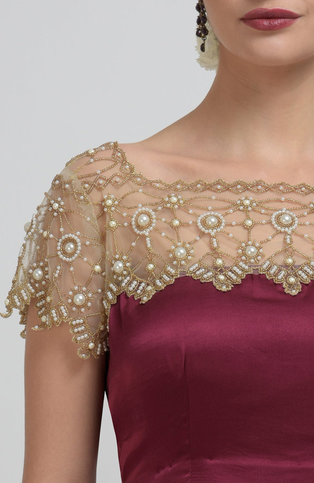 A woman models a burgundy blouse with a sheer, pearl-beaded, gold-embroidered yoke and sleeves.
