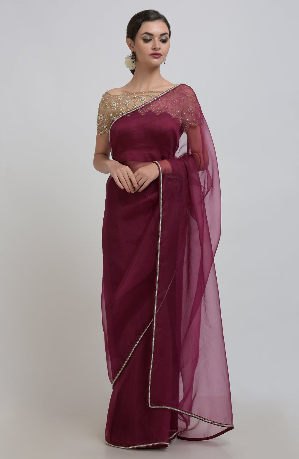 A woman models a burgundy organza silk saree with pearl bead embroidery.