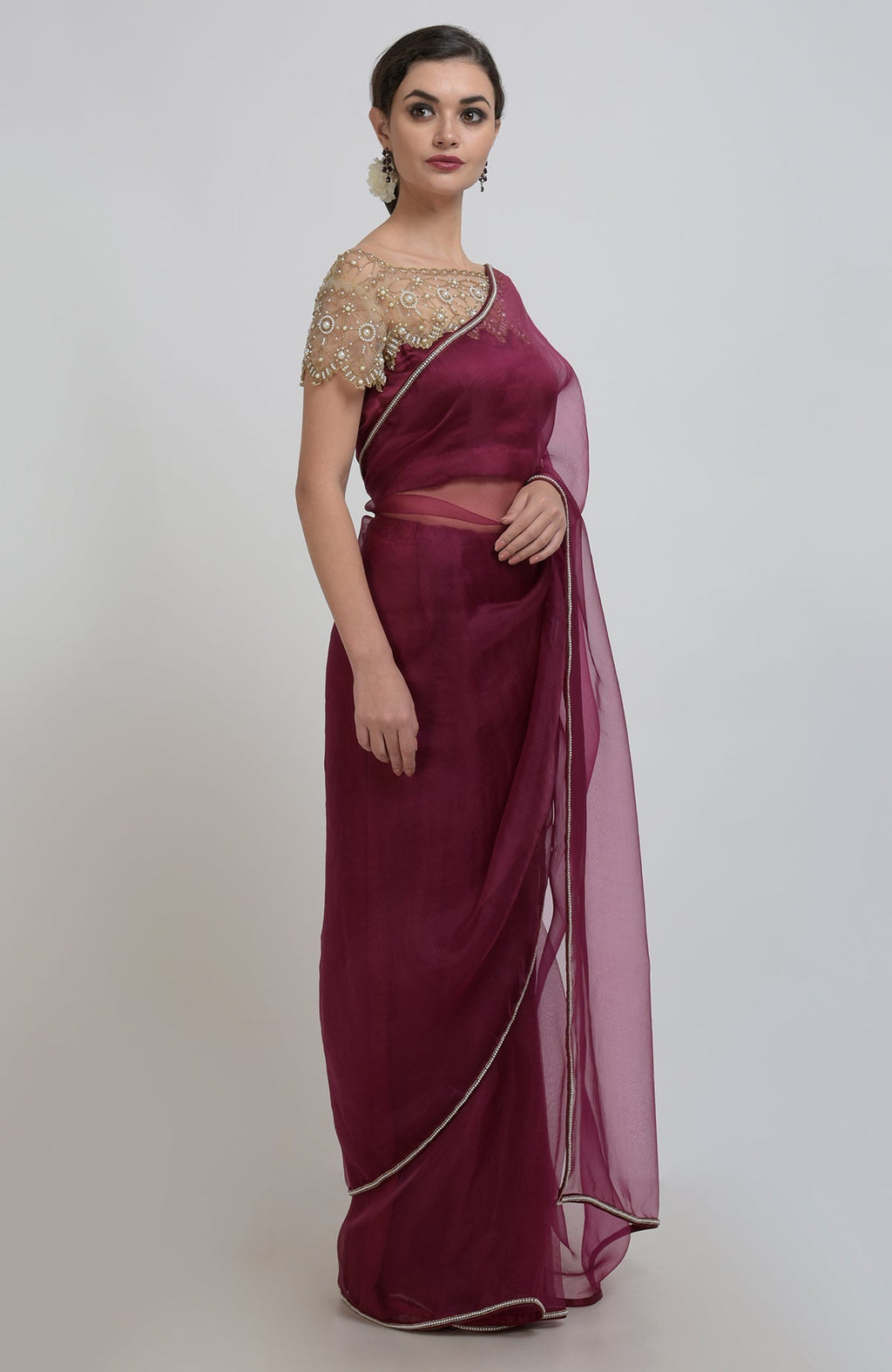A woman models a burgundy organza silk saree with a pearl-beaded blouse.