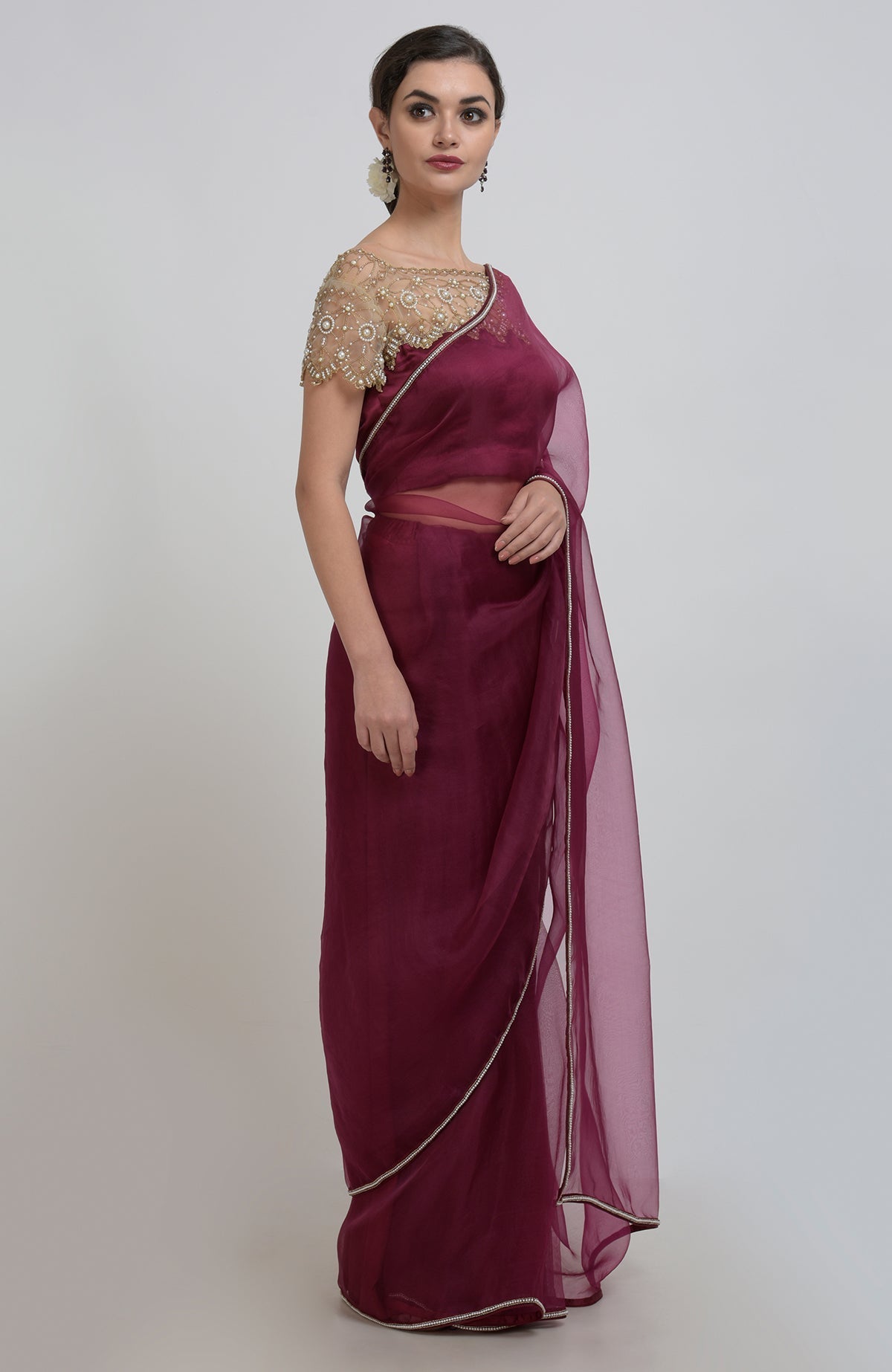 A woman models a burgundy organza silk saree with a pearl-beaded blouse.