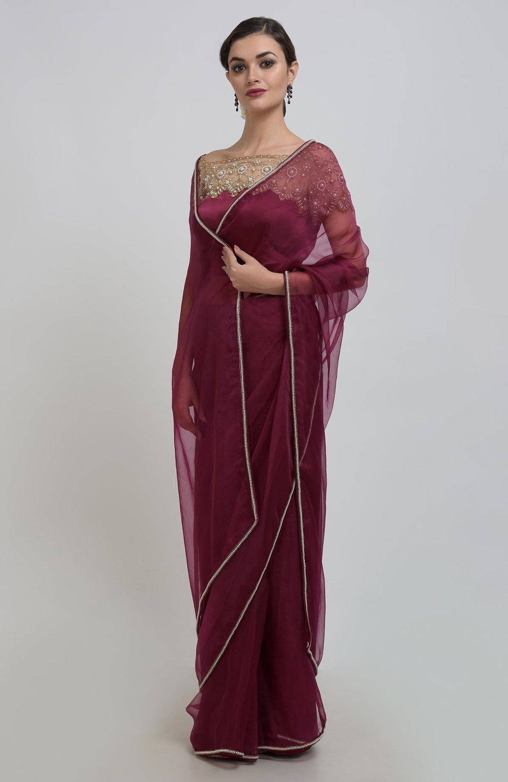 A woman models a burgundy organza silk saree with pearl bead embroidery.