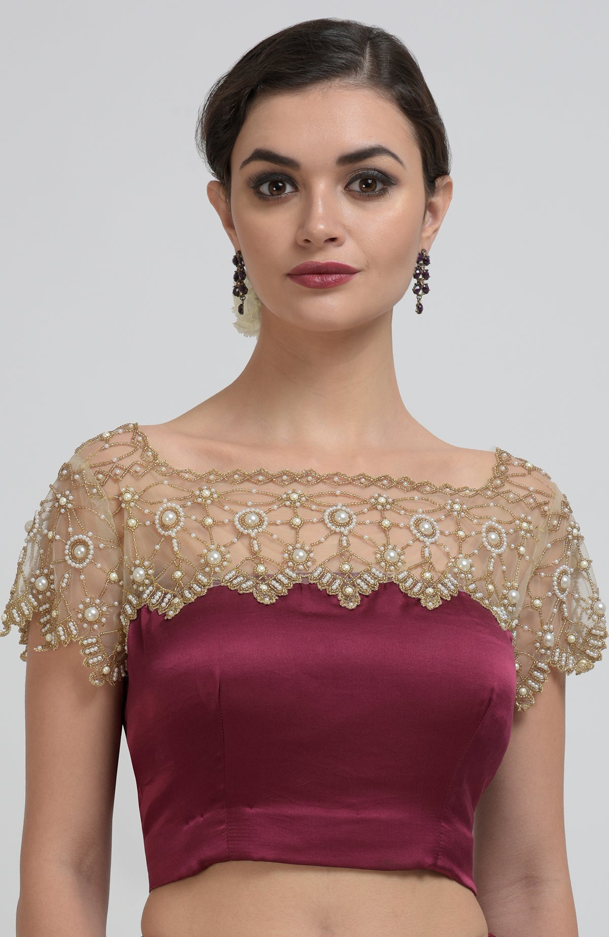 A woman models a burgundy blouse with a sheer, pearl-beaded yoke and sleeves.