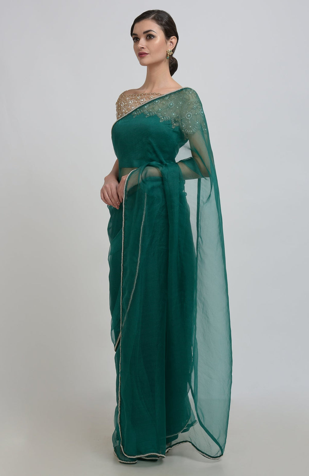 Emerald green organza silk saree with pearl bead embroidery and a matching blouse.
