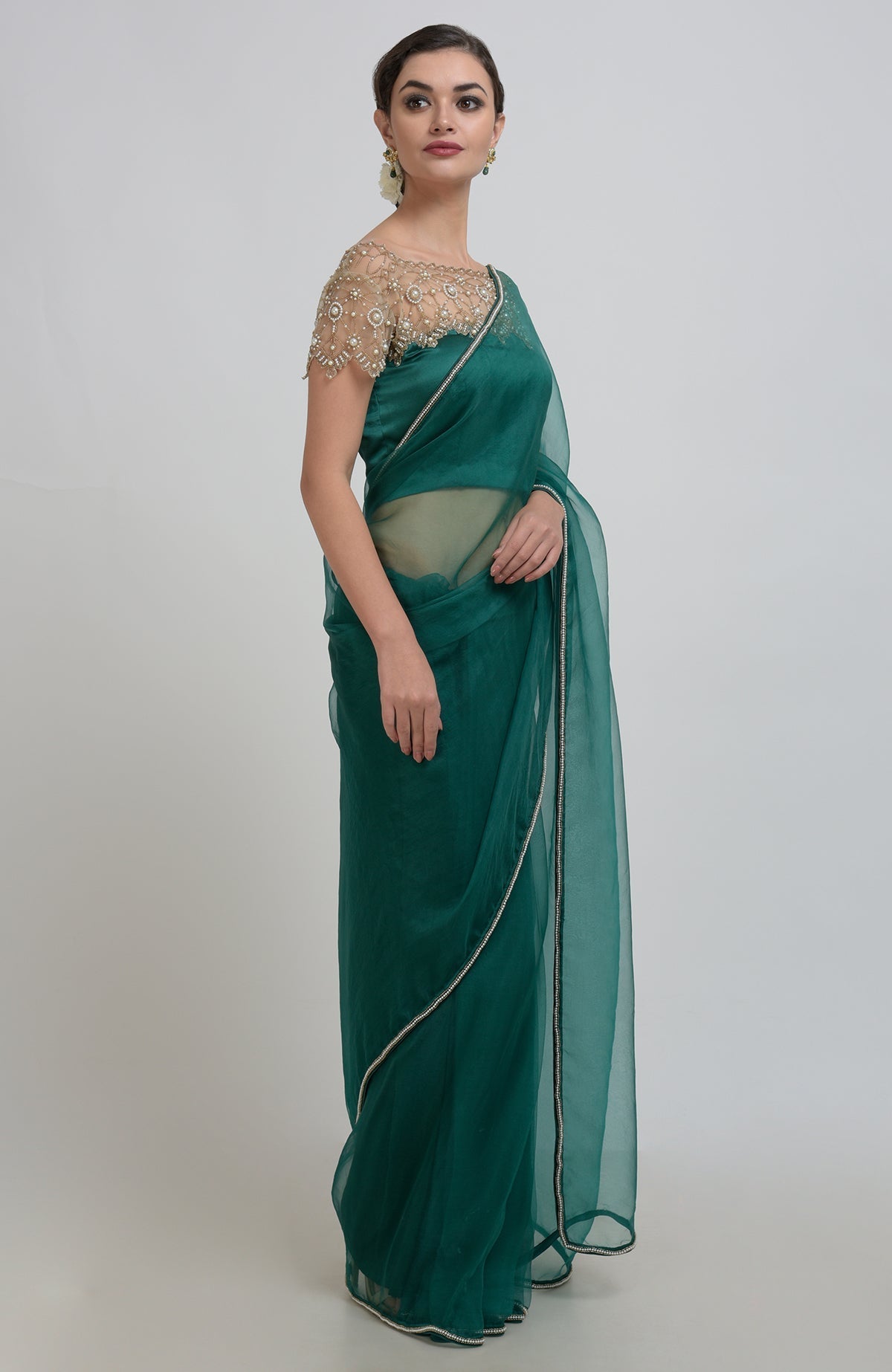 An emerald green organza saree with pearl bead embroidery and a matching blouse.