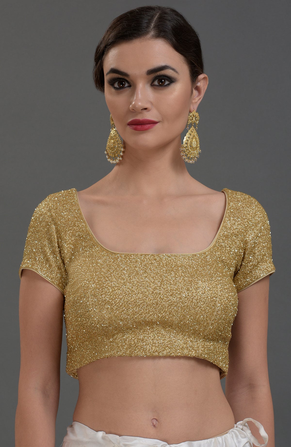 A woman models a gold georgette tissue zardozi hand-embroidered blouse with cap sleeves.