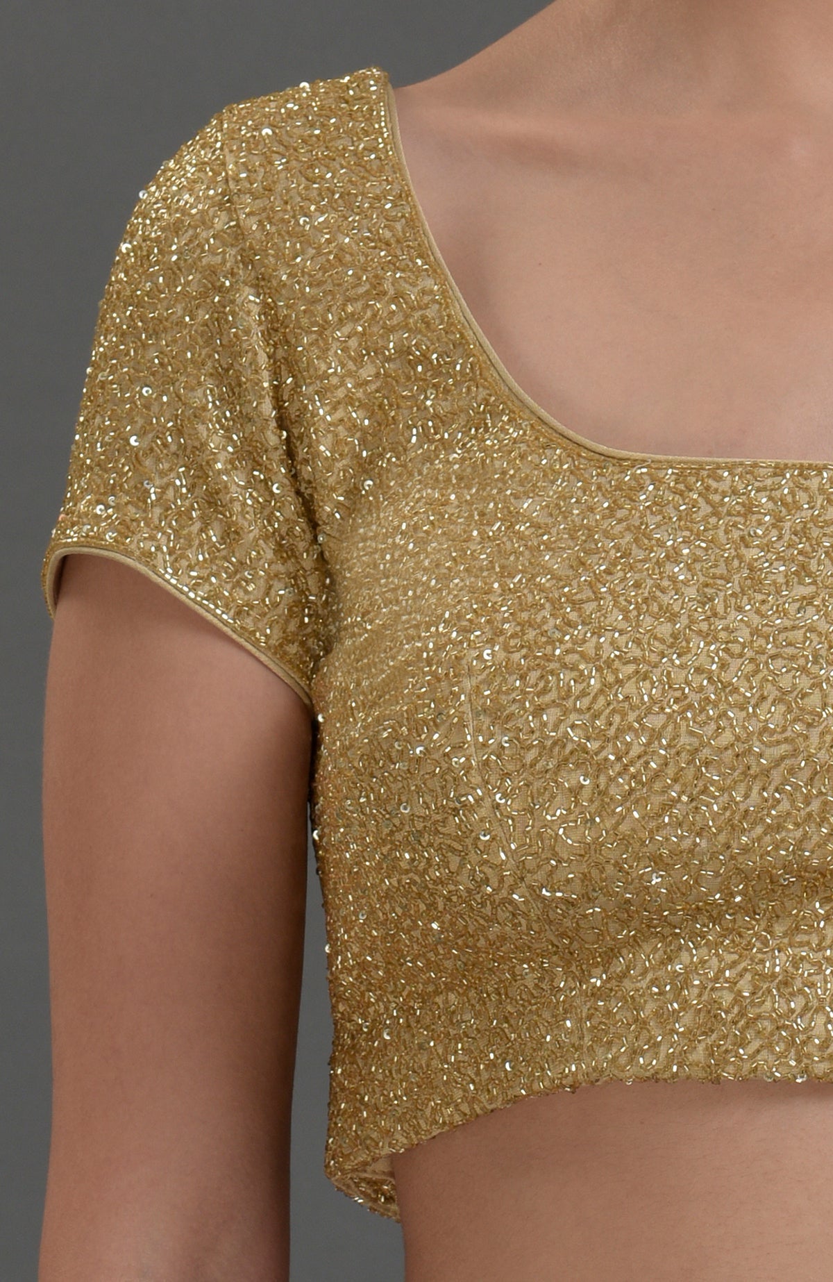 Gold georgette tissue blouse with all-over zardozi hand embroidery and cap sleeves.