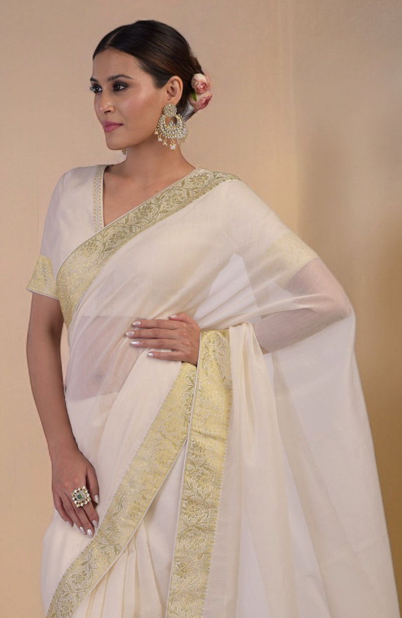 Ivory saree with gold Banarasi border and motifs, paired with gold embroidered blouse with V-neck.