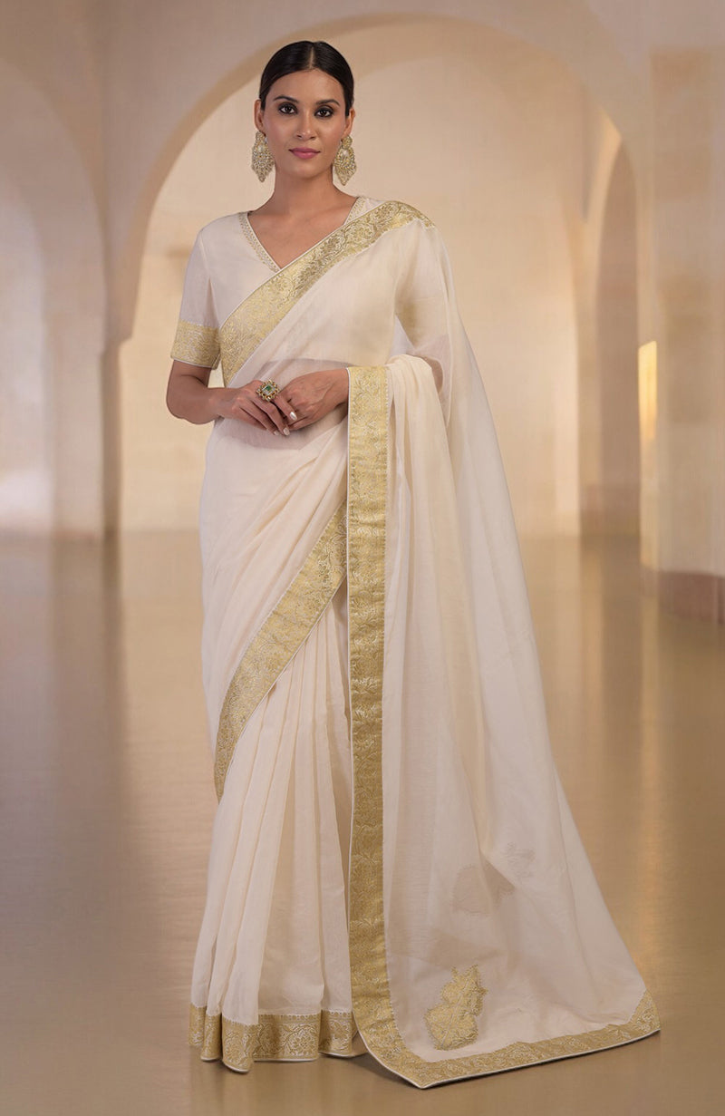 Ivory saree with gold Banarasi border and motifs, paired with embroidered blouse with V-neck.