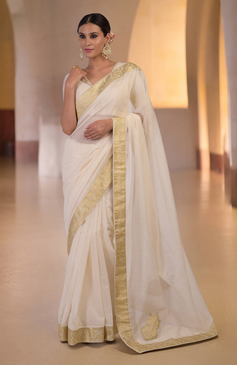 Ivory saree with gold Banarasi border and motifs, paired with embroidered blouse with V-neck.