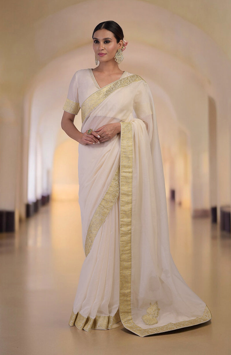 Ivory saree with gold Banarasi border and motifs, paired with embroidered V-neck blouse.