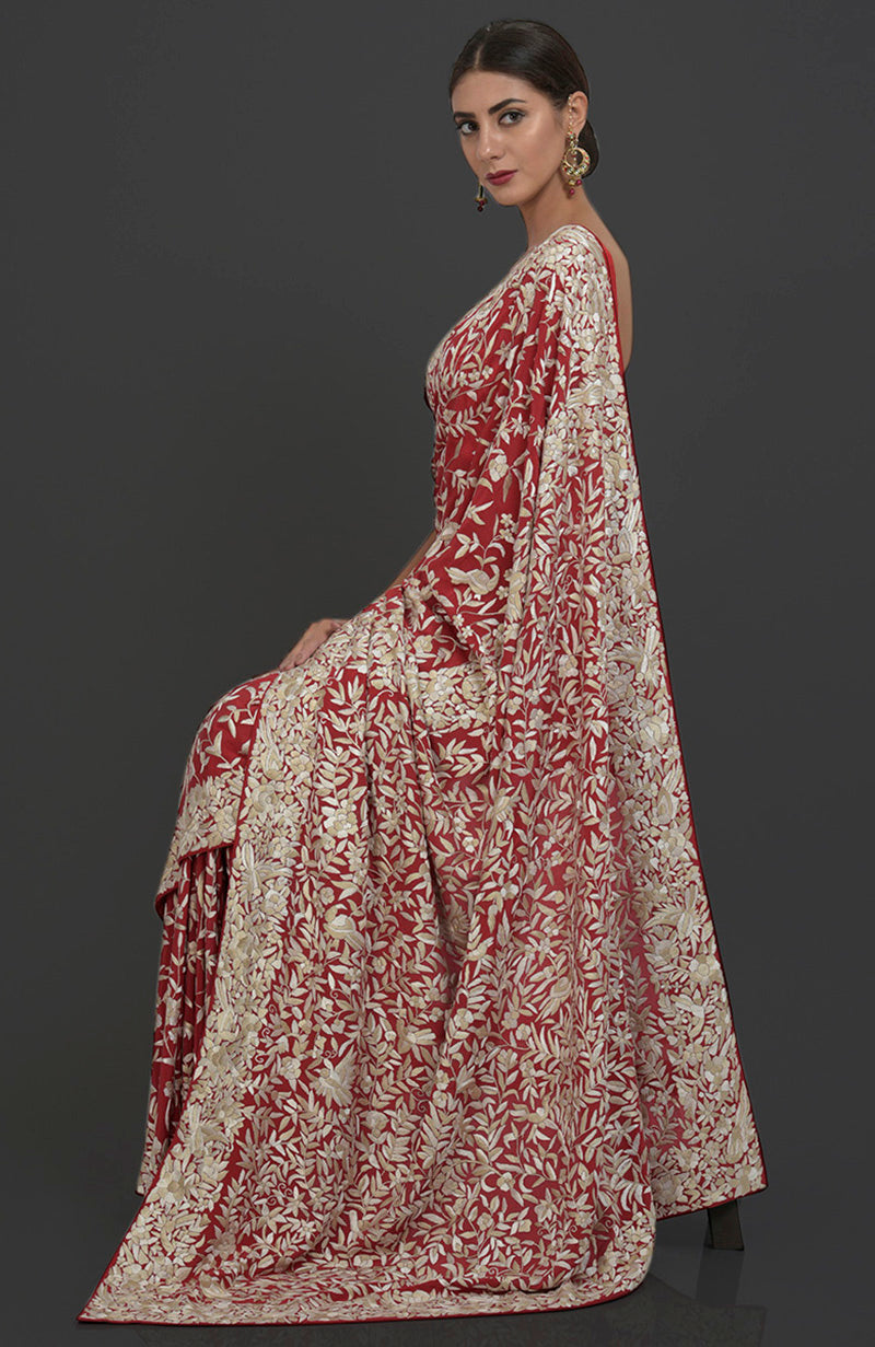 A woman models a red Parsi Gara hand-embroidered saree with floral and bird motifs.