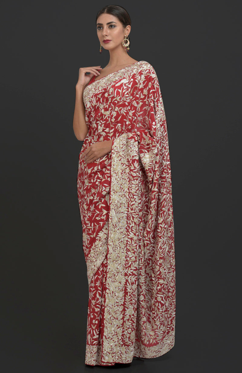 A woman models a red Parsi Gara hand-embroidered saree with white floral patterns.