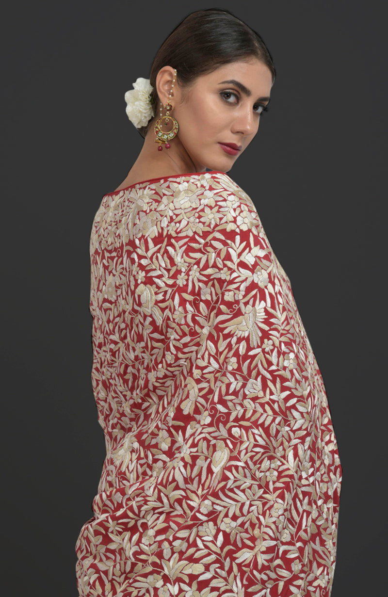 A woman models a red Parsi Gara hand-embroidered saree with floral and bird patterns.