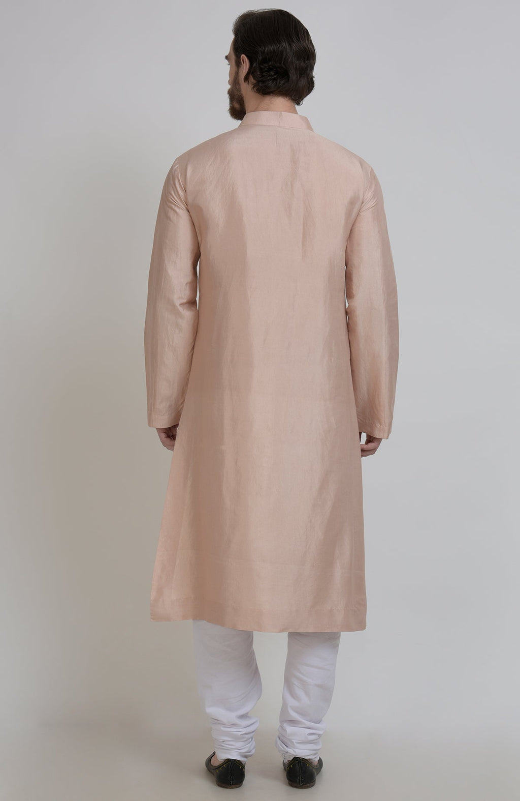 A man from behind wears an oyster pink silk kurta and white churidar pants.