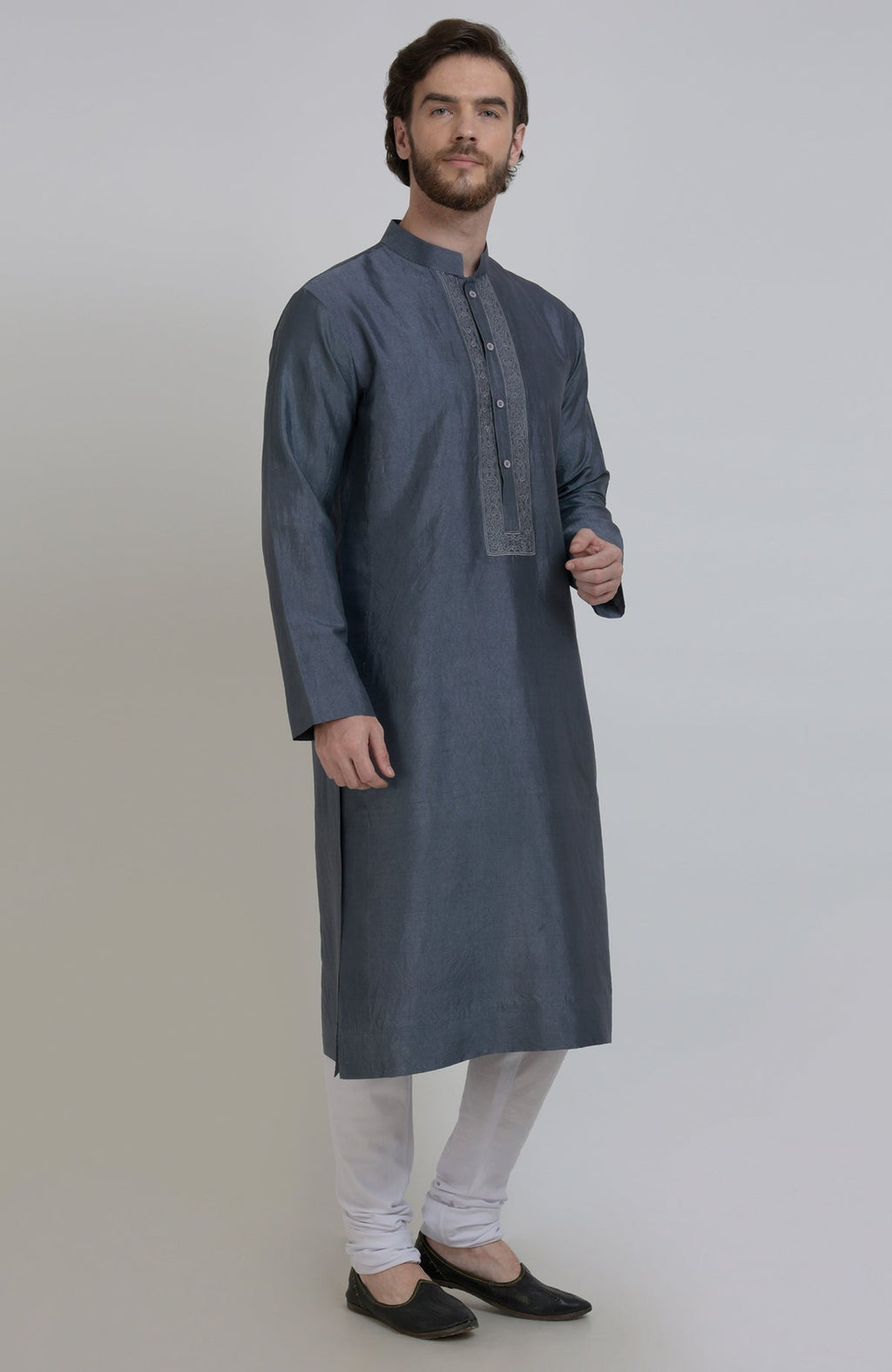 Grey silk kurta with an embroidered placket, paired with white churidar pants and black shoes.