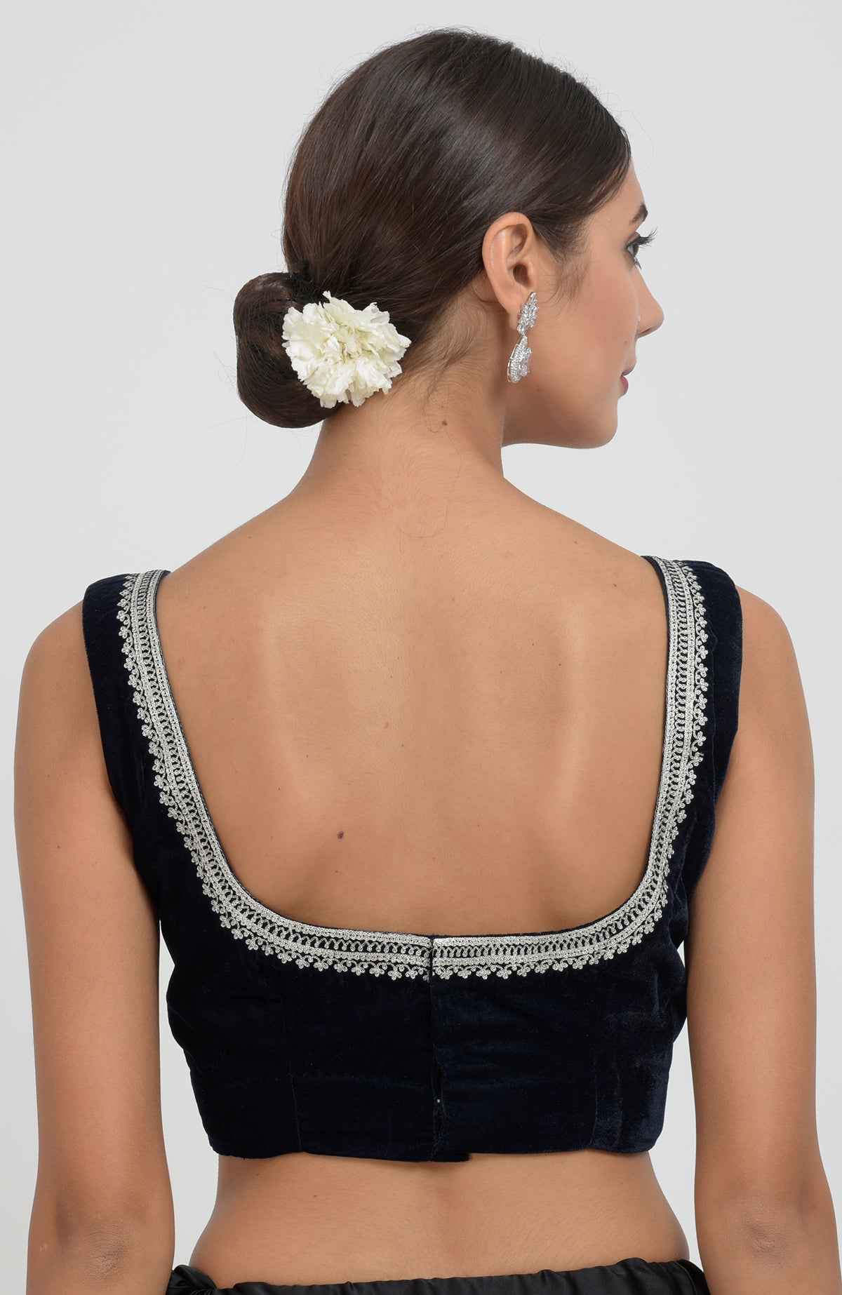A woman models a midnight blue velvet blouse with silver tilla aari embroidery on the back.