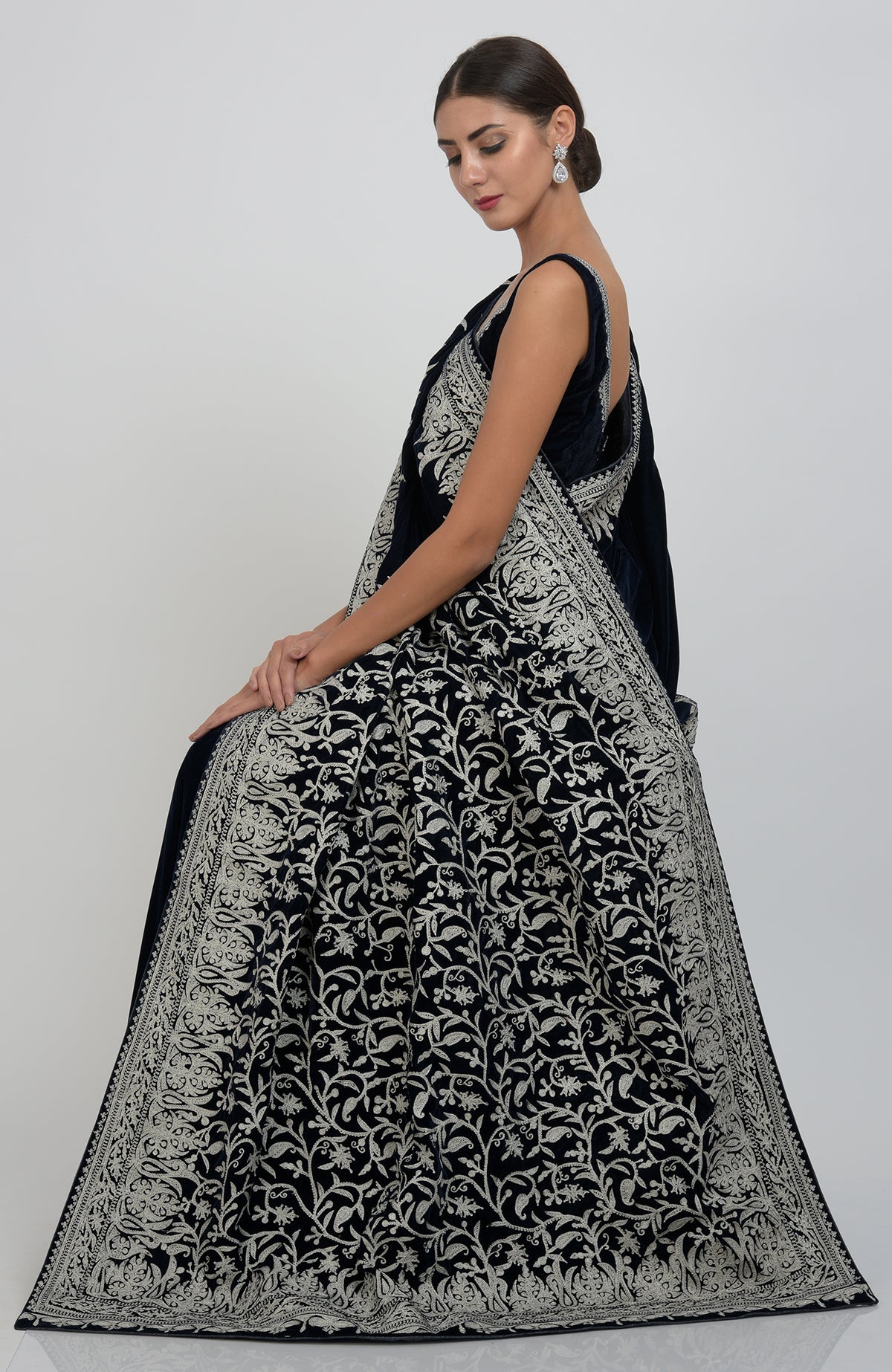 A woman models a midnight blue velvet saree with silver tilla aari embroidery.