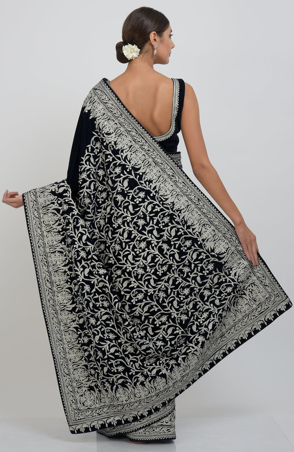 A woman models a midnight blue velvet saree with silver tilla aari embroidery.