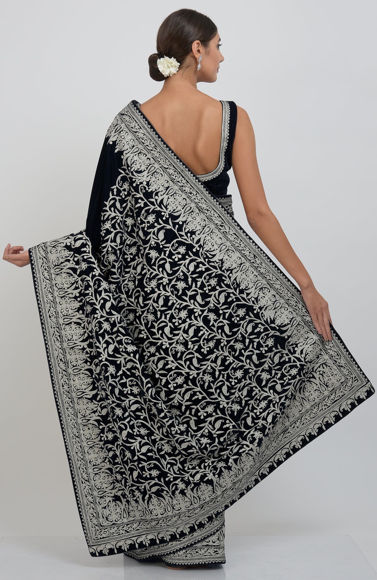 A woman models a midnight blue velvet saree with silver tilla aari embroidery.