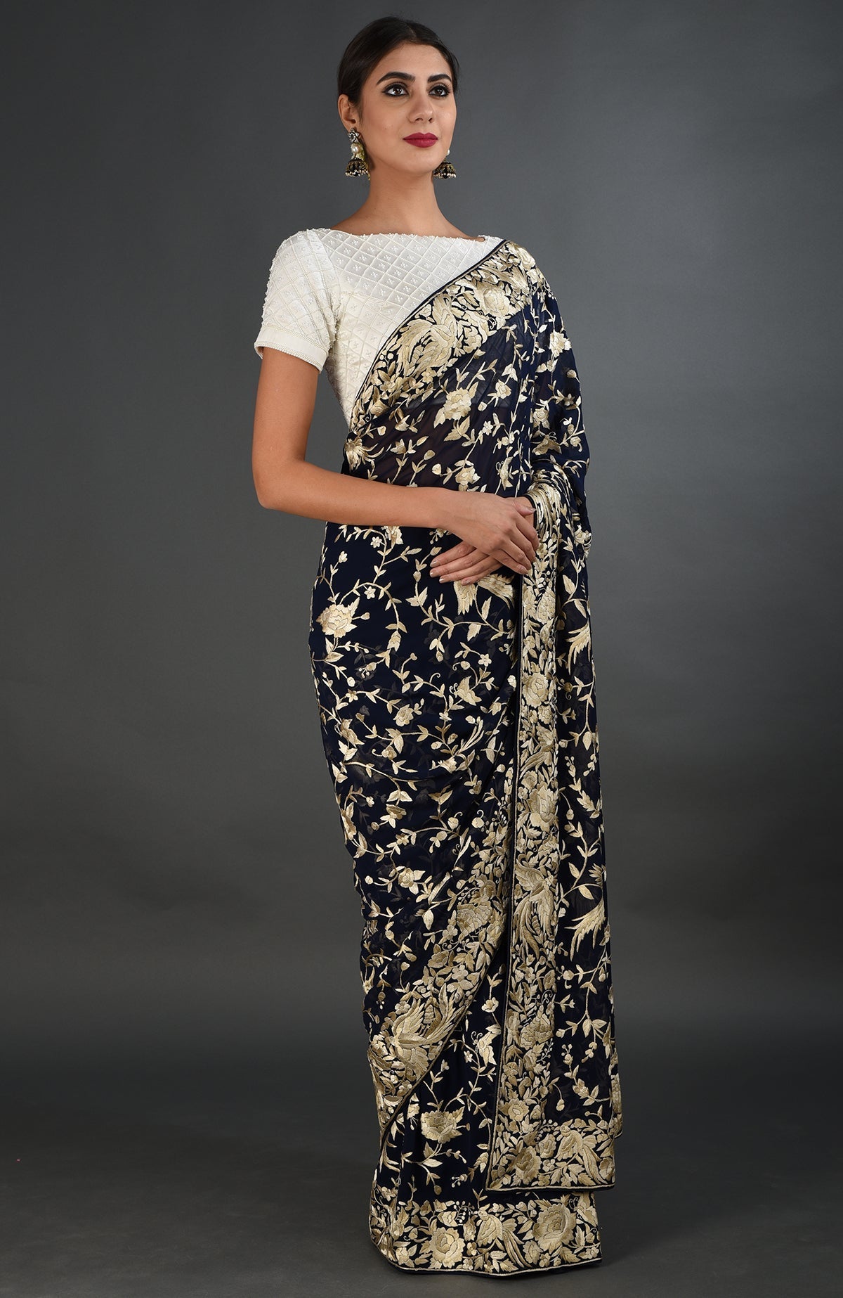 A woman models a midnight blue Parsi Gara hand-embroidered saree with a white blouse.